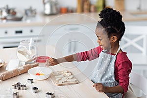 Little black girl baking cookies alone at home