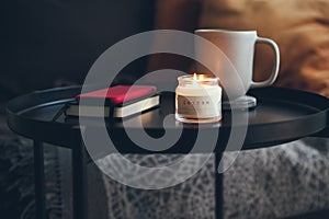 Little black raund table next to the sofa with cup of delicious hot chocalate / cacao drink and candlelight. Relaxing after work