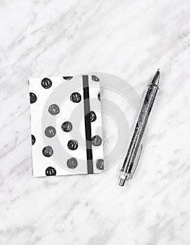 Black and white diary and pen on marble background