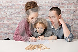 Little blond boy drawing with his parents