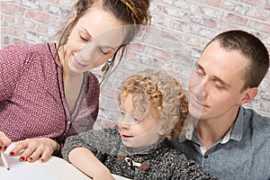 Little blond boy drawing with his parents