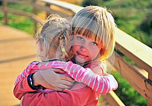 Little blond boy hugging his sister outdoors