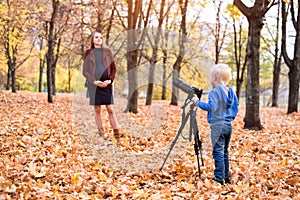 Little blond boy with a large reflex camera on a tripod. Photographs a pregnant woman. Family photo session