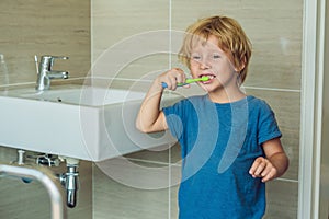 Little blond boy learning brushing his teeth in domestic bath. Kid learning how to stay healthy. Health care concept