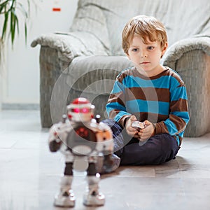 Little blond boy playing with robot toy at home, indoor.