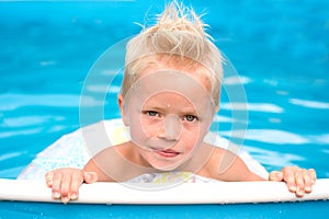 little blond boy is in swimming pool with inflable ring photo