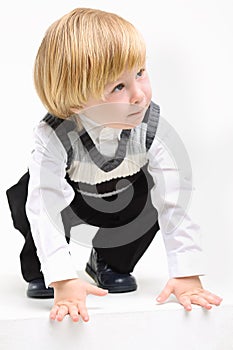 Little blond boy in vest is squat and looks upward