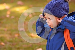 Little blond boy wearing warm blue hat and blue