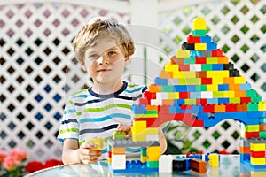 Little blond child and kid boy playing with lots of colorful plastic blocks.