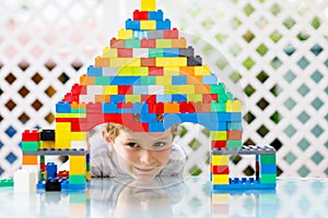 Little blond child and kid boy playing with lots of colorful plastic blocks.