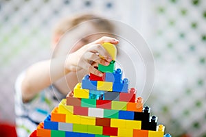 Little blond child and kid boy playing with lots of colorful plastic blocks.