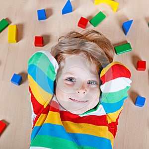 Little blond child playing with colorful wooden blocks indoor