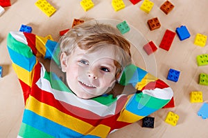 Little blond child playing with lots of colorful plastic blocks