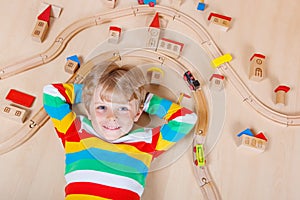 Little blond child playing with wooden railroad trains indoor