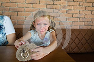 Little blond crying girl with sad expression and tears