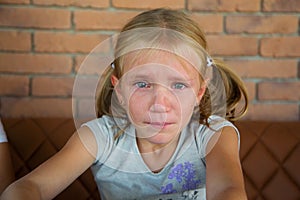 Little blond crying girl with sad expression and tears
