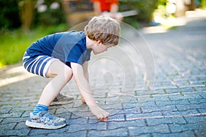 Little blond funny kid boy playing hopscotch on playground outdoors
