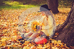 Little blond girl and big pumpkin in autumn background.