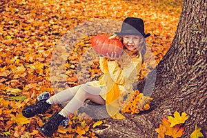 Little blond girl and big pumpkin in autumn background.