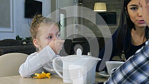 Little blond girl drinking tea sitting in cafe with her lovely parents.