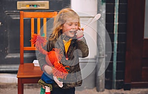 Little blond girl and her orange hair doll on King`s Day festivity, Netherlands