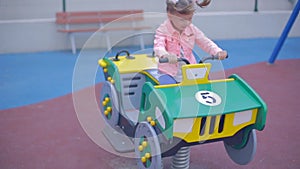 Little blond girl in jeans plays in a children`s park.