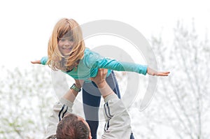 Little blond girl lifted high in the air by her father outdoor photo