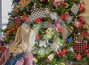 Little blond girl mesmerized by decorated Christmas tree