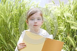 Little blond girl reading book green spikes garden