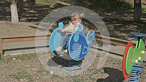 Little blond girl riding the spring rider at playground