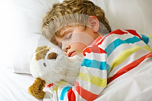 Little blond kid boy in colorful nightwear clothes sleeping