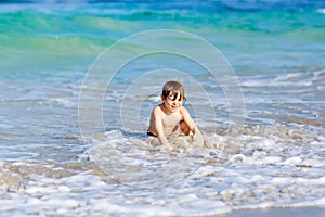 Little blond kid boy having fun on ocean beach in Florida