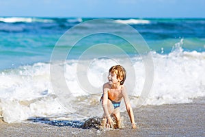 Little blond kid boy having fun on ocean beach in Florida