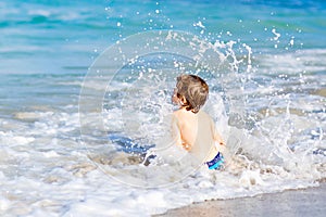 Little blond kid boy having fun on ocean beach in Florida