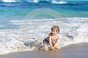 Little blond kid boy having fun on ocean beach in Florida