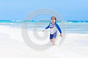 Little blond kid boy having fun on tropical beach of Maldives