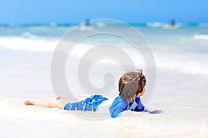 Little blond kid boy having fun on tropical beach of Seychelles
