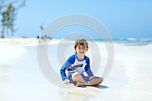 Little blond kid boy having fun on tropical beach of Thailand
