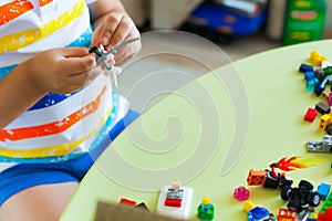 Little blond kid boy playing with lots of colorful plastic block