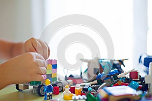 Little blond kid boy playing with lots of colorful plastic block