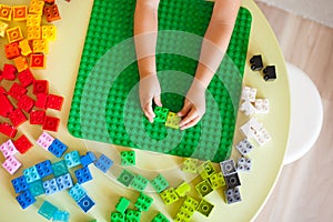 Little blond kid boy playing with lots of colorful plastic block