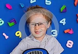 Little blond toddler child playing with lots of colorful plastic digits or numbers, indoor. Kid boy wearing colorful