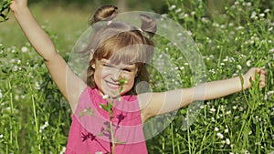 Little blonde child girl in pink dress stay on flower chamomile grass meadow. Bouquet of daisies