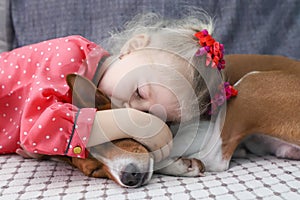 Little blonde curly girl hugging a basenji dog.