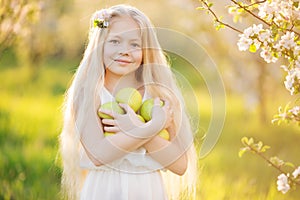 Little blonde girl in blossom apple tree garden