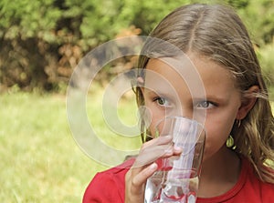 Little blonde girl, drinks water from a glass