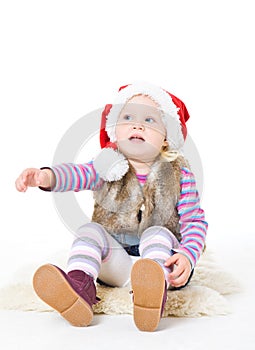 Little blonde girl in a fur jacket and a red Santa's cap