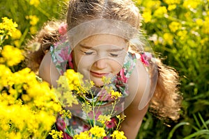 Little blonde girl inhales scent of flowers