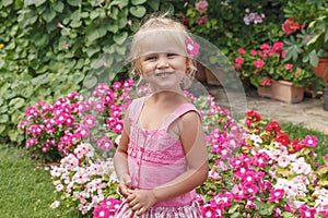 Little blonde girl in a pink dress with flower in her hair