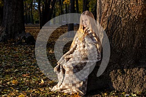 little blonde girl in a plaid whip in the park in autumn